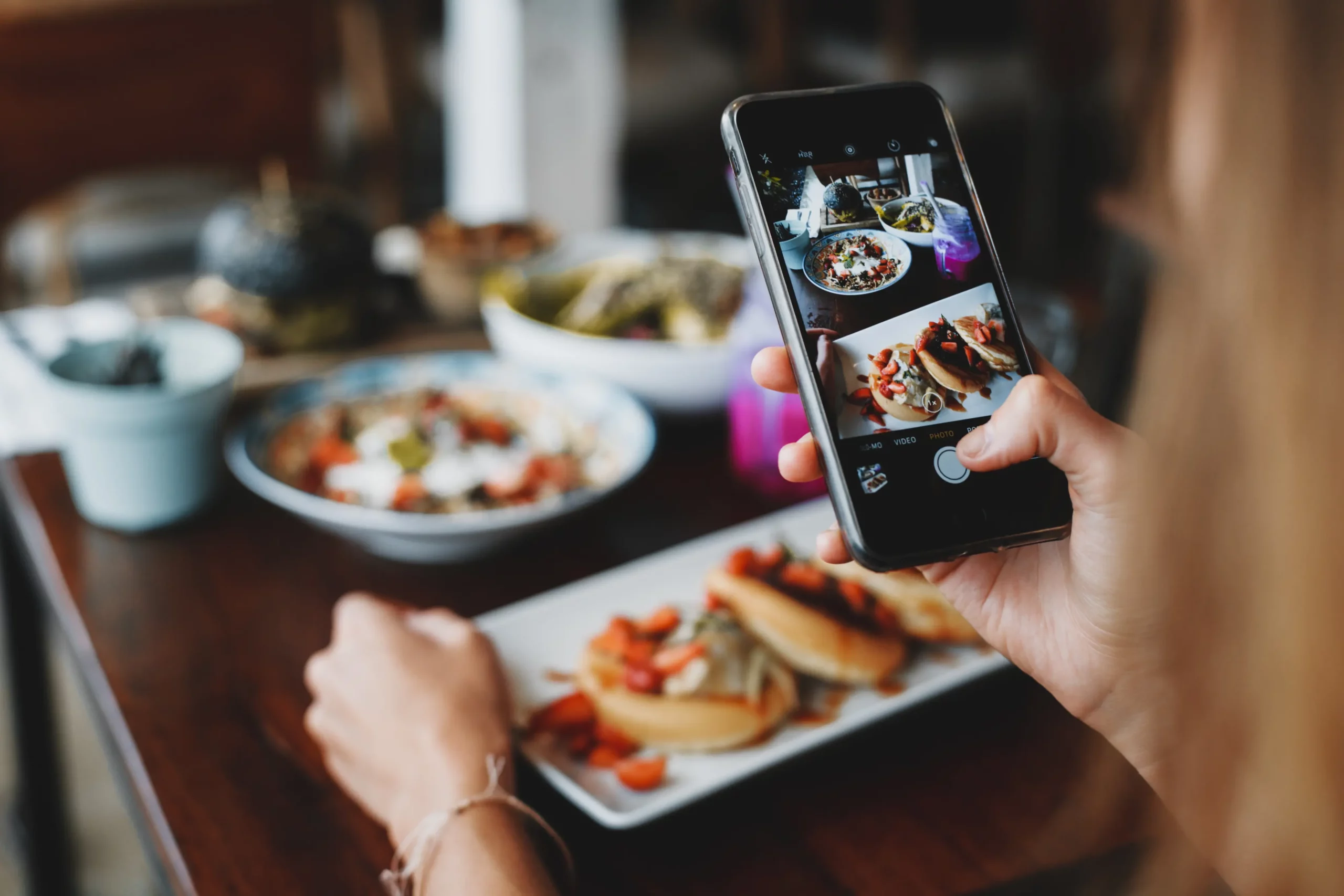 image of a woman taking a photo of her food with a phone