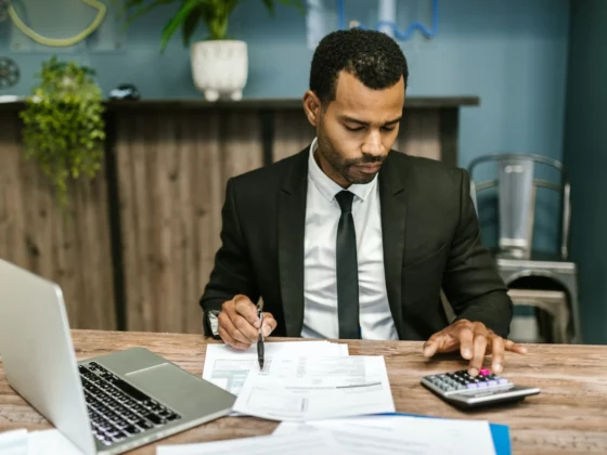 man in a suit sat doing sums on a calculator at a desk