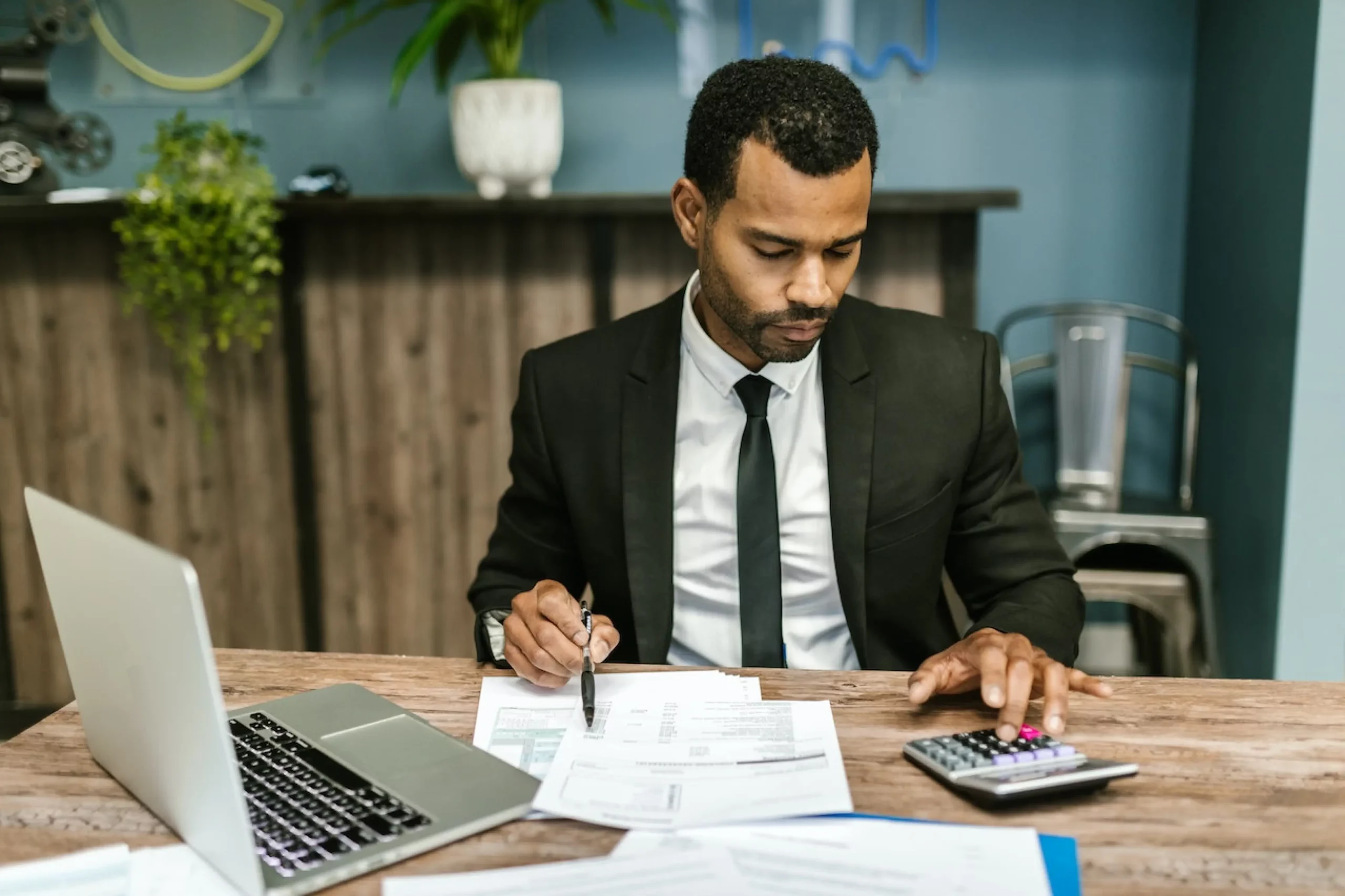 man in a suit sat doing sums on a calculator at a desk