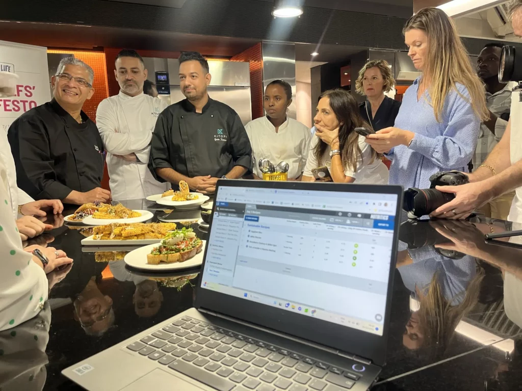 image of people gathering round a laptop in a kitchen