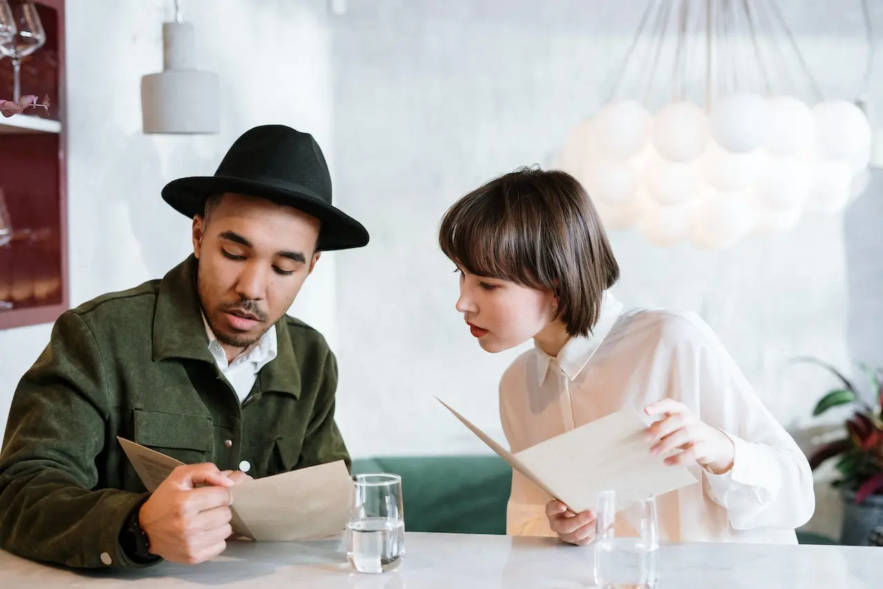 two people looking at a menu in a cafe