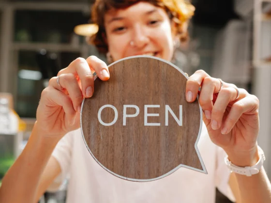 woman holding a sign which says the word open on it