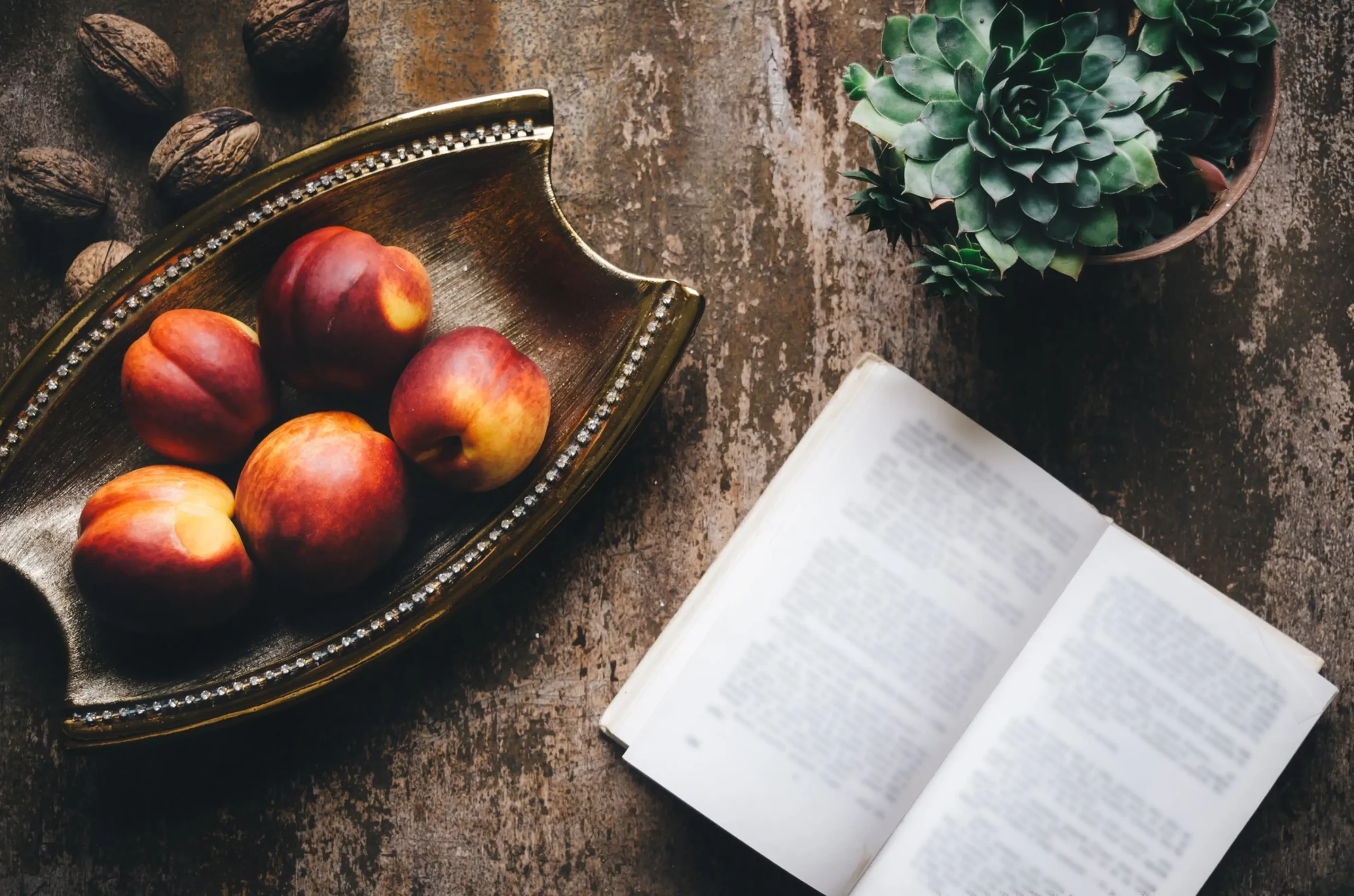 image of peaches, a plant and a book on a table