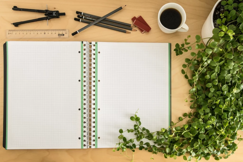 image from above of blank notebook with plants and stationery