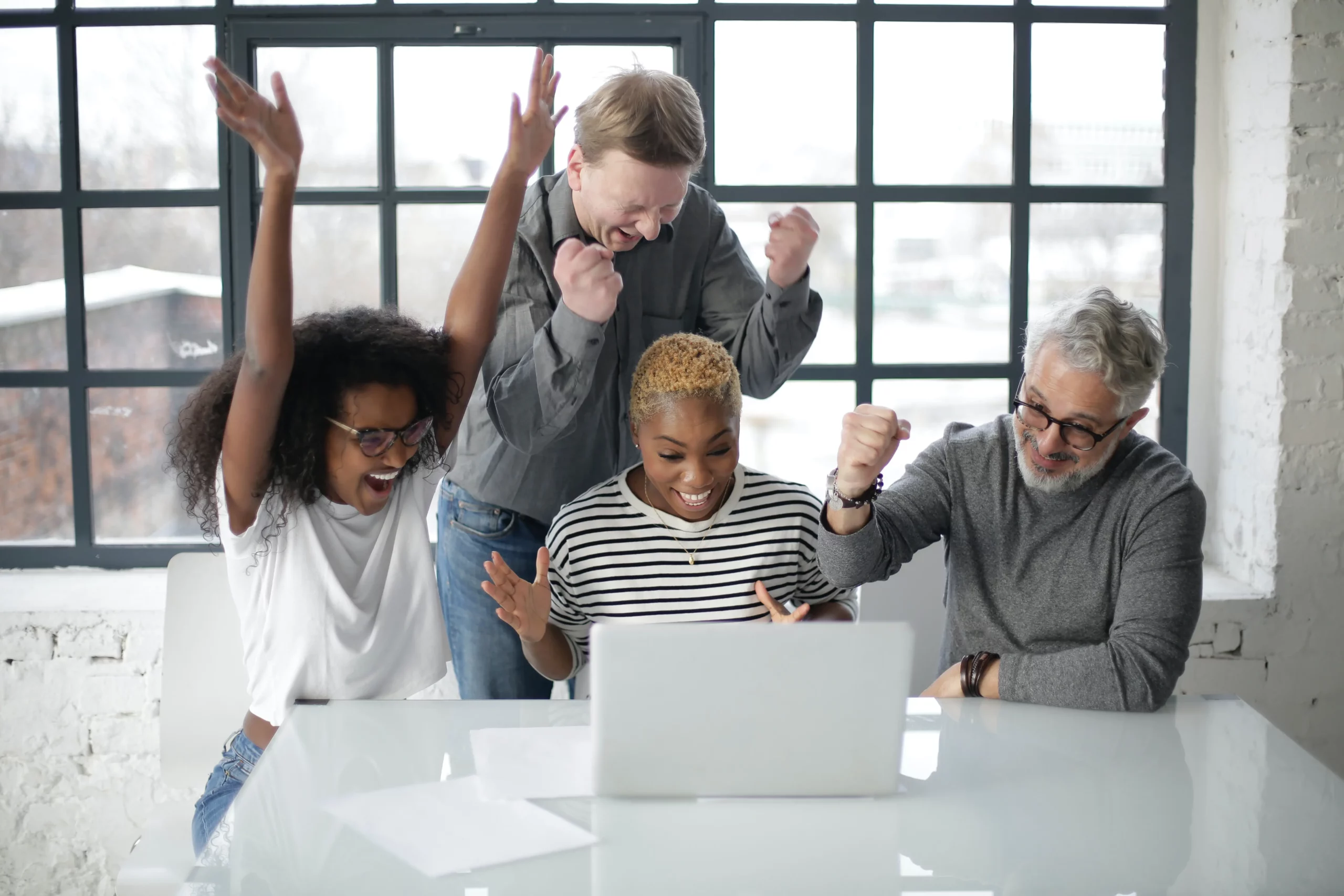 group of people stood around a laptop cheering