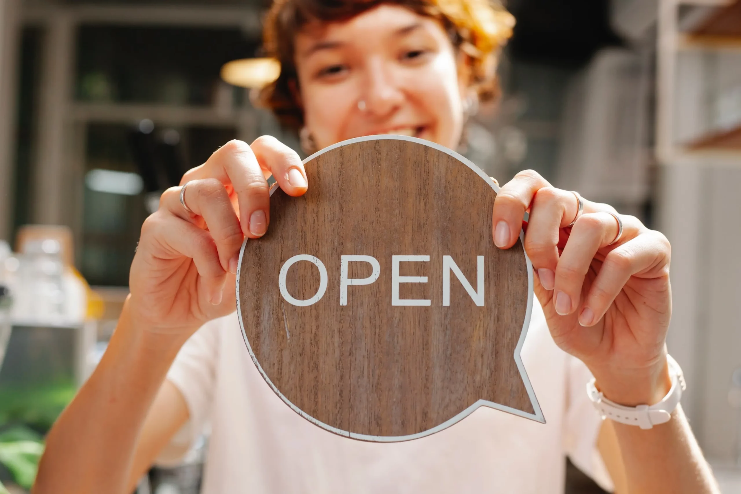 woman holding a sign which says the word open on it