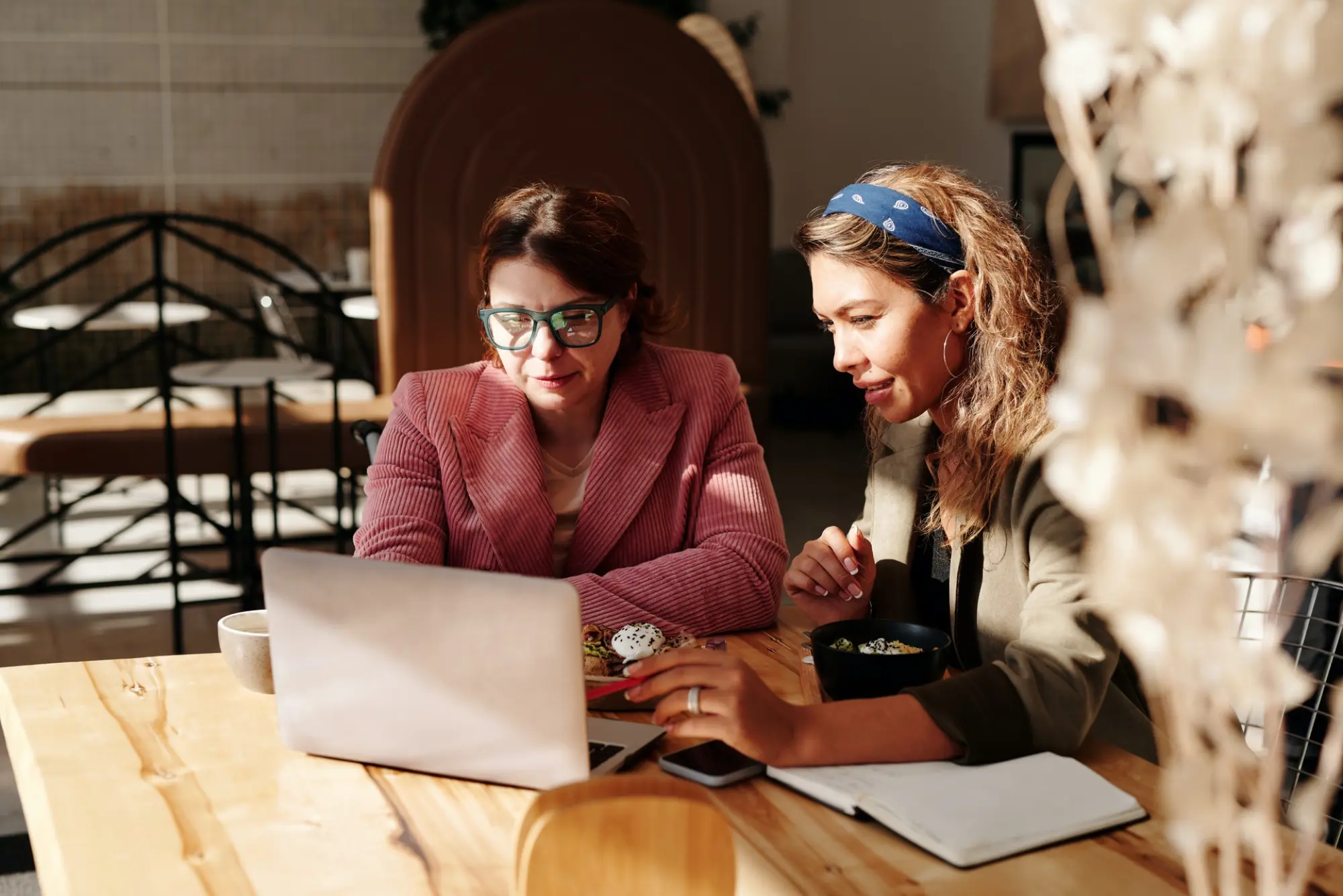 two women looking at laptop in a cafe