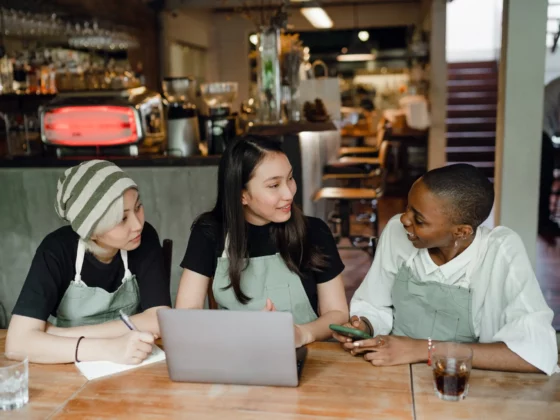 three restaurant staff talking around a laptop