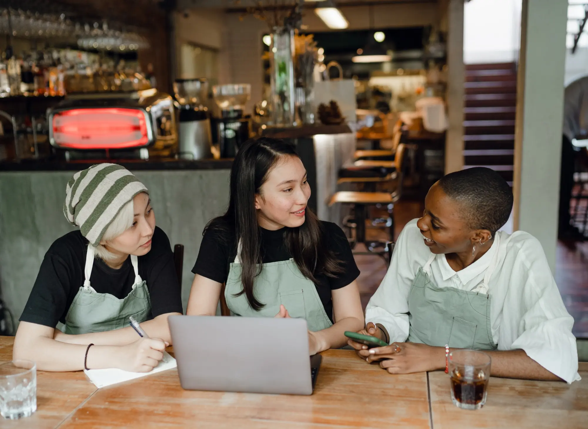 three restaurant staff talking around a laptop