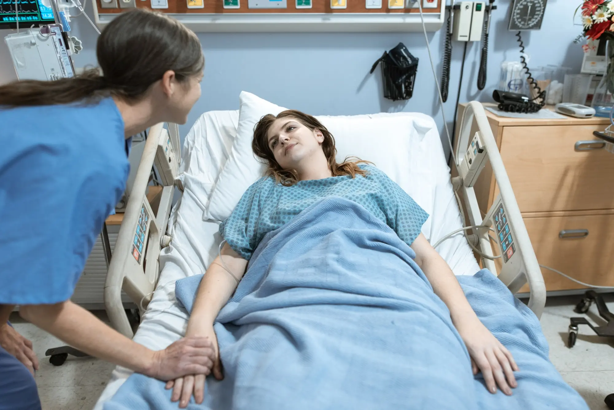 patient laying in hospital bed with nurse