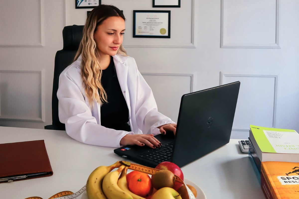 nutritionist on laptop using Nutritics software for sports nutrition with fruit on desk