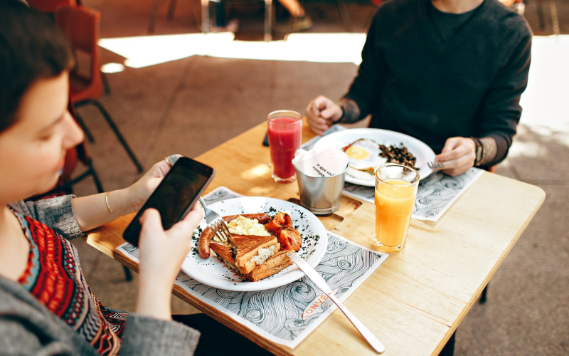 image of someone taking a photo of their lunch while eating in a restaurant